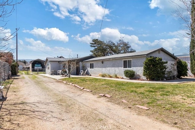 ranch-style house featuring a front yard, fence, driveway, and stucco siding