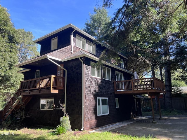 view of property exterior featuring a deck, stairway, and a patio area