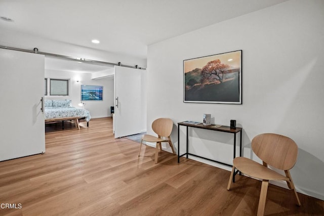 living area with a barn door, recessed lighting, wood finished floors, and baseboards