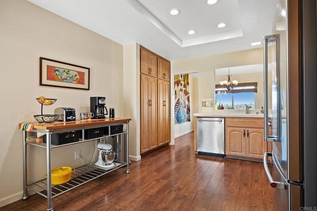 kitchen with light countertops, a tray ceiling, recessed lighting, appliances with stainless steel finishes, and dark wood-style flooring