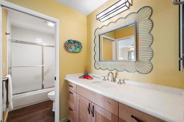 full bathroom with vanity, toilet, wood finished floors, and combined bath / shower with glass door