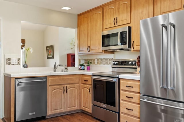 kitchen featuring a sink, light countertops, decorative backsplash, appliances with stainless steel finishes, and dark wood-style flooring