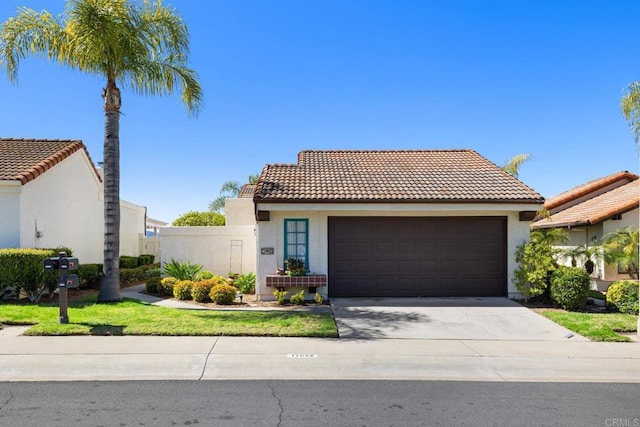 view of front of property with a tiled roof, stucco siding, driveway, and an attached garage