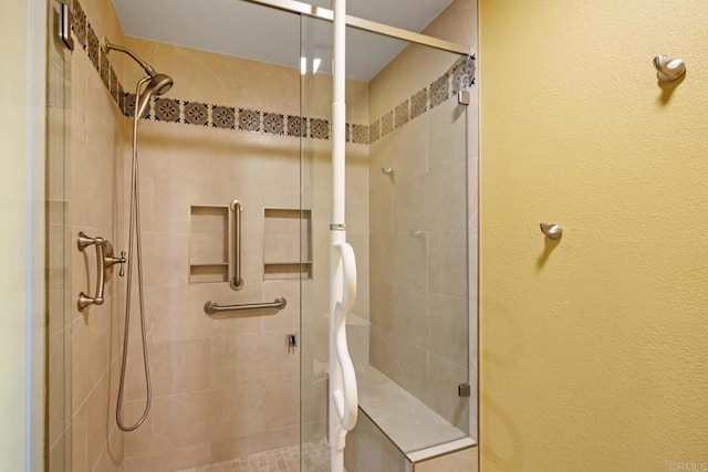 full bath with a shower stall and a textured wall