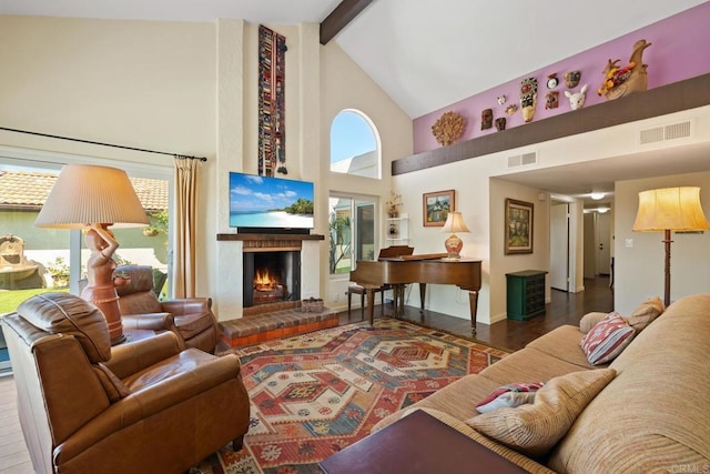 living area with beam ceiling, visible vents, a brick fireplace, and wood finished floors