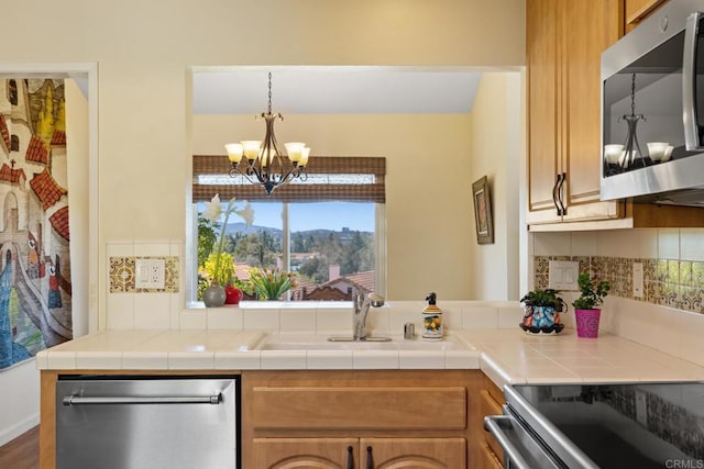 kitchen featuring tile countertops, brown cabinetry, tasteful backsplash, and stainless steel appliances