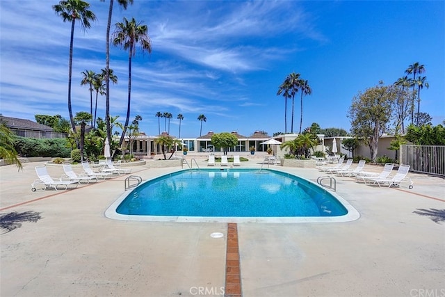 pool with a patio area and fence