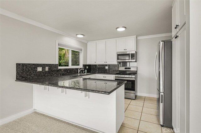 31711 Crystal Sands Dr, Laguna Niguel, CA 92677 - kitchen with appliances with stainless steel finishes, a peninsula, ornamental molding, dark stone counters, and tasteful backsplash