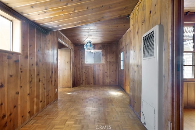 hall with visible vents, wooden walls, a healthy amount of sunlight, and a heating unit