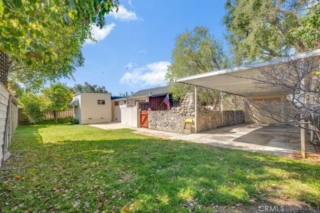 view of yard with an outbuilding, a fenced backyard, a carport, and a shed