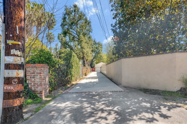 view of street featuring driveway and a gate