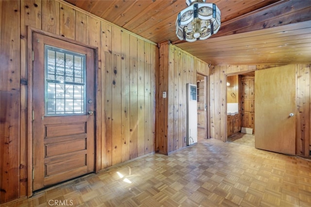 entrance foyer featuring wooden walls, wooden ceiling, and baseboards