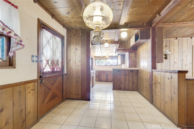 interior space with light tile patterned floors, brown cabinets, wooden walls, and wooden ceiling