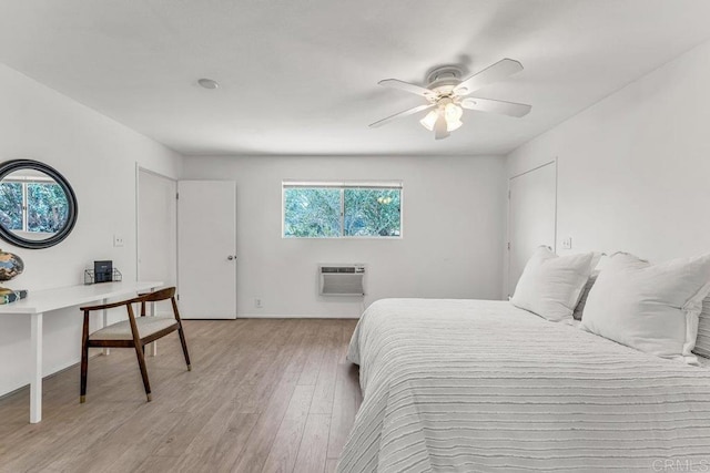 bedroom featuring light wood-style flooring, a ceiling fan, and a wall mounted AC