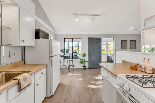 kitchen with washer / dryer, white cabinets, light countertops, and vaulted ceiling