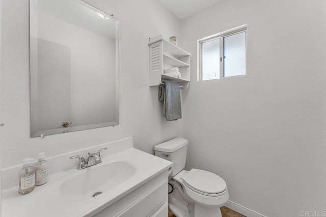 half bathroom with toilet, vanity, and baseboards