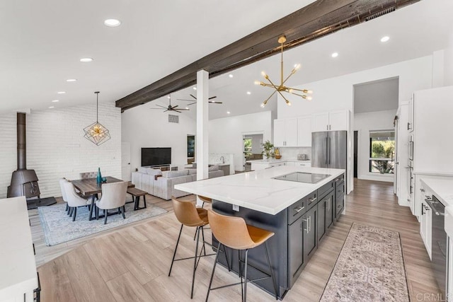 kitchen with stainless steel appliances, white cabinetry, beamed ceiling, decorative light fixtures, and ceiling fan with notable chandelier