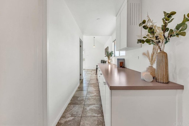 corridor with baseboards and lofted ceiling