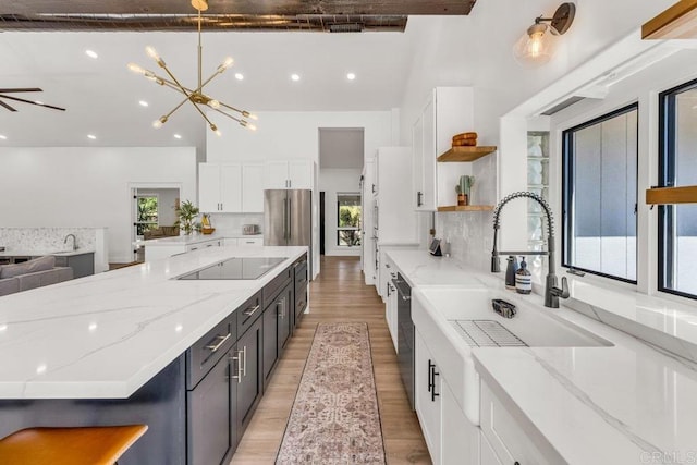 kitchen featuring open shelves, stainless steel fridge, light wood-style floors, white cabinets, and black electric stovetop