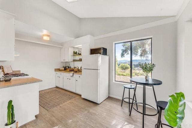 kitchen featuring white appliances, lofted ceiling, open shelves, a sink, and light wood-style floors