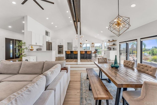 living area with light wood finished floors, beamed ceiling, recessed lighting, a notable chandelier, and high vaulted ceiling