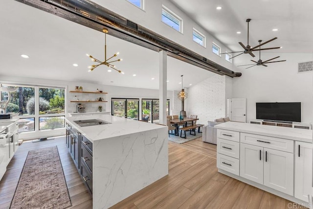 kitchen with a center island, open floor plan, light wood-type flooring, a towering ceiling, and white cabinetry