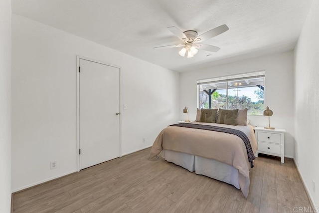 bedroom with a textured ceiling, a ceiling fan, and light wood-style floors