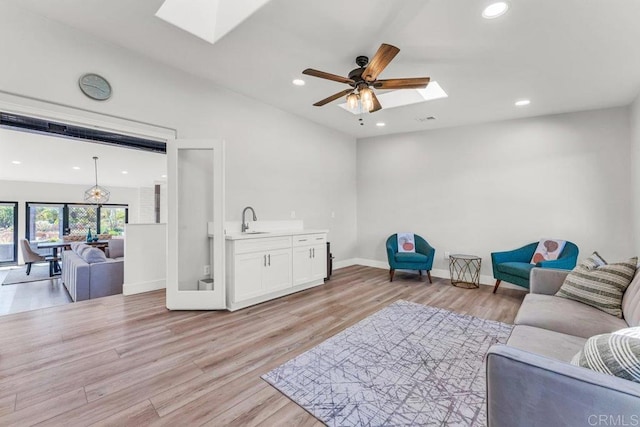 living area with a skylight, recessed lighting, and light wood-style flooring