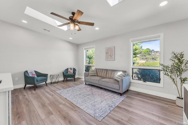 living area featuring a skylight, recessed lighting, light wood-style floors, and visible vents