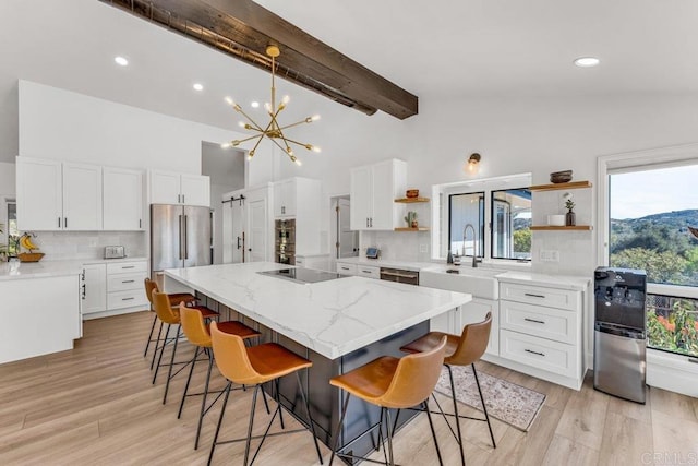 kitchen with open shelves, a sink, a kitchen island, stainless steel appliances, and a breakfast bar area