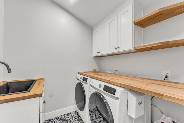 clothes washing area with washing machine and dryer, cabinet space, baseboards, and a sink