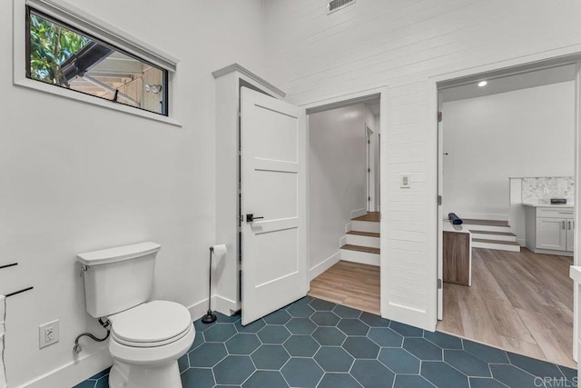 bathroom with visible vents, toilet, wood finished floors, and baseboards