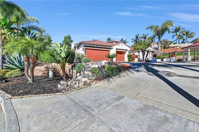 view of front of home with stucco siding, a tile roof, driveway, and fence