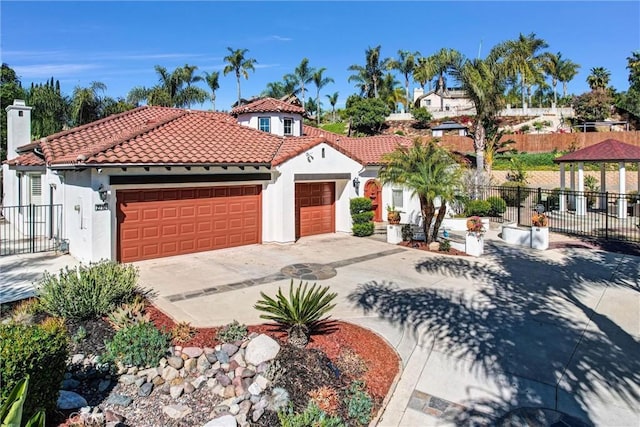 mediterranean / spanish house with stucco siding, fence, a gazebo, an attached garage, and a tiled roof