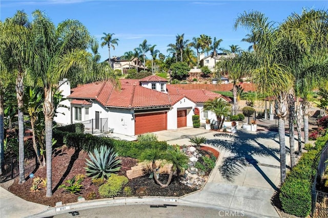 mediterranean / spanish-style home featuring fence, concrete driveway, a tile roof, stucco siding, and a garage