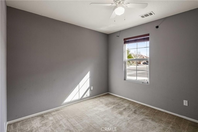 empty room featuring carpet flooring, baseboards, visible vents, and ceiling fan