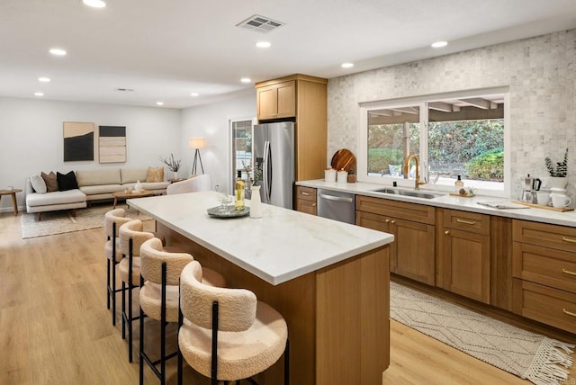 kitchen featuring visible vents, a sink, a kitchen island, appliances with stainless steel finishes, and a breakfast bar area