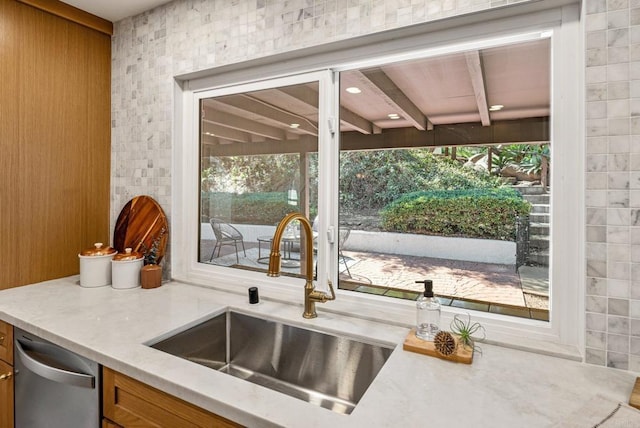 kitchen featuring light stone countertops, a sink, built in desk, dishwasher, and brown cabinets