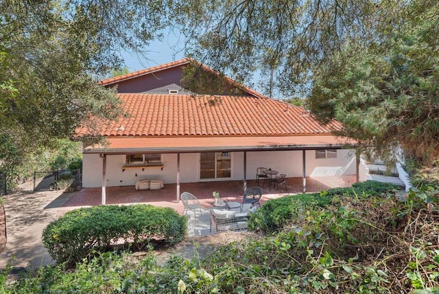 rear view of house with a patio area, a tiled roof, and fence