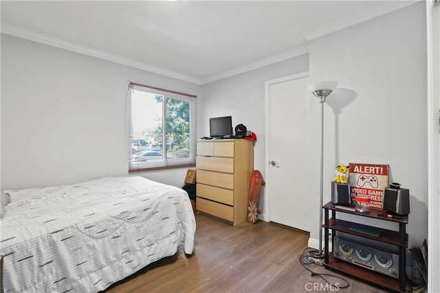 bedroom featuring baseboards, wood finished floors, and ornamental molding