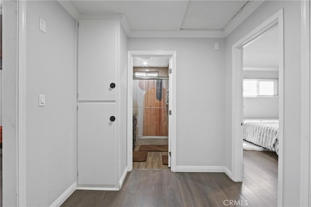 hallway featuring dark wood-style floors, crown molding, and baseboards