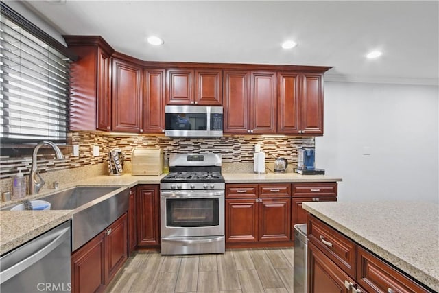 kitchen with a sink, decorative backsplash, reddish brown cabinets, and appliances with stainless steel finishes