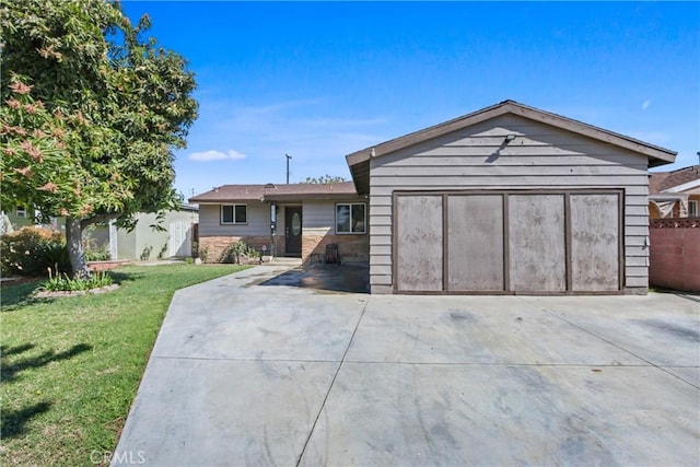 ranch-style house featuring a front yard, concrete driveway, fence, and an attached garage