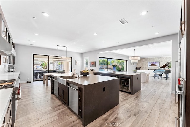 kitchen featuring a sink, visible vents, dark brown cabinets, and a center island with sink