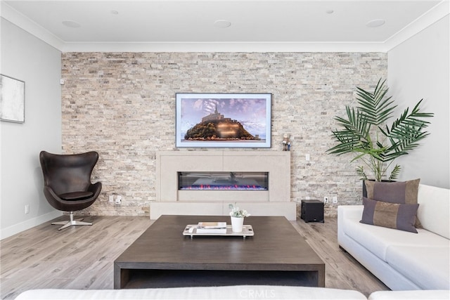 living area featuring baseboards, wood finished floors, a glass covered fireplace, and ornamental molding