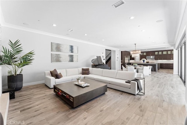 living area featuring visible vents, baseboards, ornamental molding, recessed lighting, and light wood-style flooring