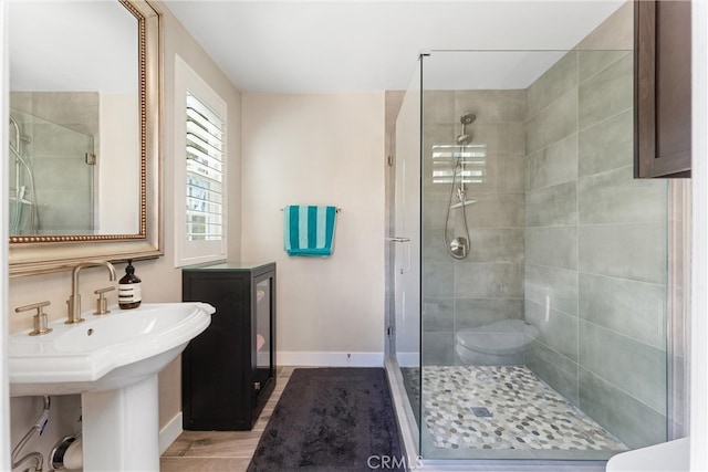 bathroom with a sink, baseboards, and a stall shower