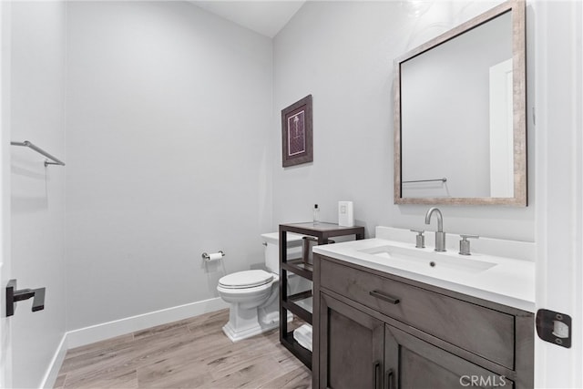 bathroom featuring vanity, toilet, wood finished floors, and baseboards