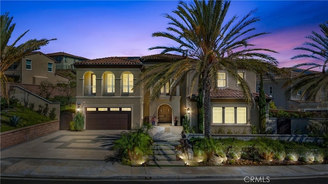 mediterranean / spanish home featuring a tile roof, concrete driveway, a garage, and stucco siding