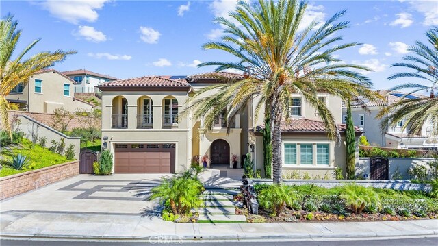 mediterranean / spanish house featuring a balcony, fence, driveway, and stucco siding